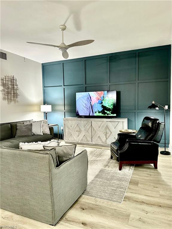 Living room with a decorative wall, wood finished floors, and ceiling fan