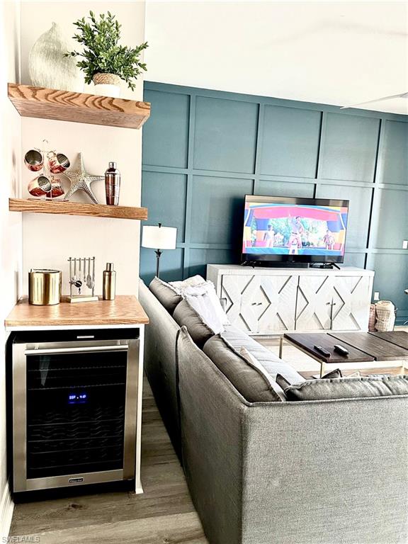 Living area featuring a decorative wall, beverage cooler, and wood finished floors