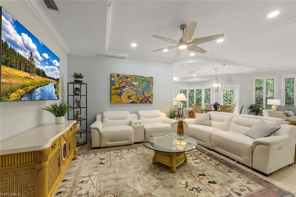 Living room with ornamental molding, recessed lighting, a ceiling fan, and a chandelier