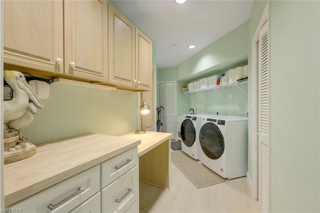 Laundry area with recessed lighting, washer and clothes dryer, light wood finished floors, and cabinet space