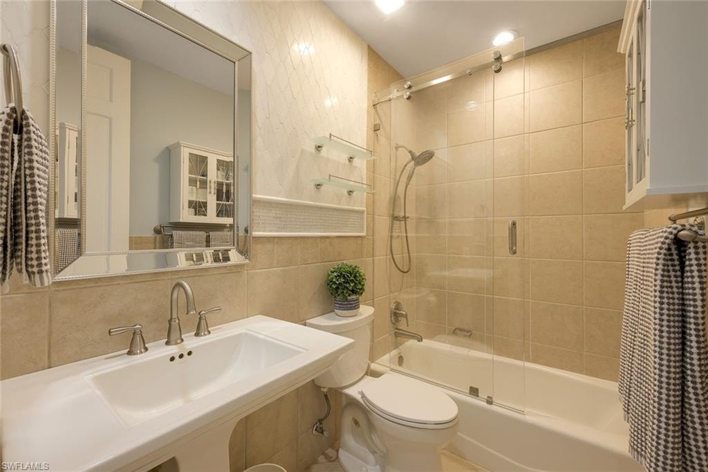 Full bath with shower / bath combination with glass door, tile walls, and tasteful backsplash