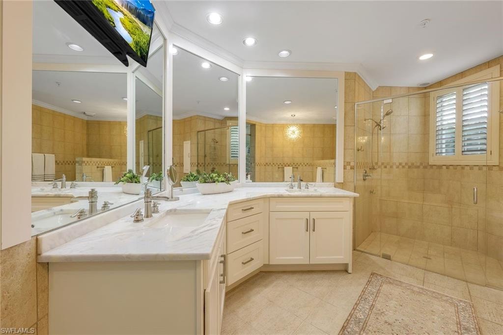 Bathroom featuring a stall shower, two vanities, crown molding, recessed lighting, and light tile patterned floors