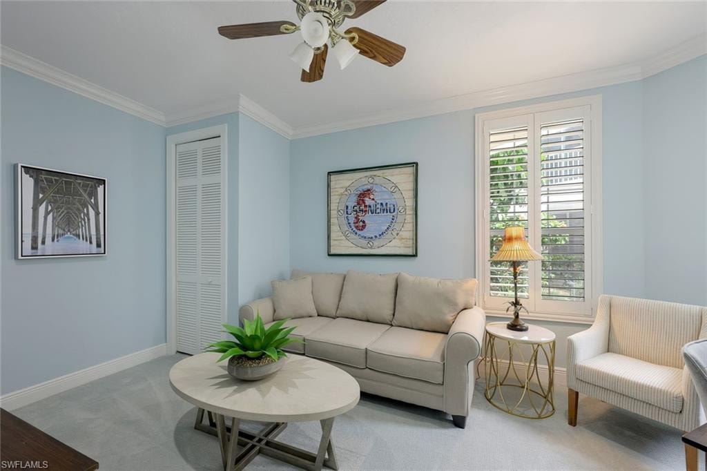 Living room with carpet flooring, crown molding, and a ceiling fan