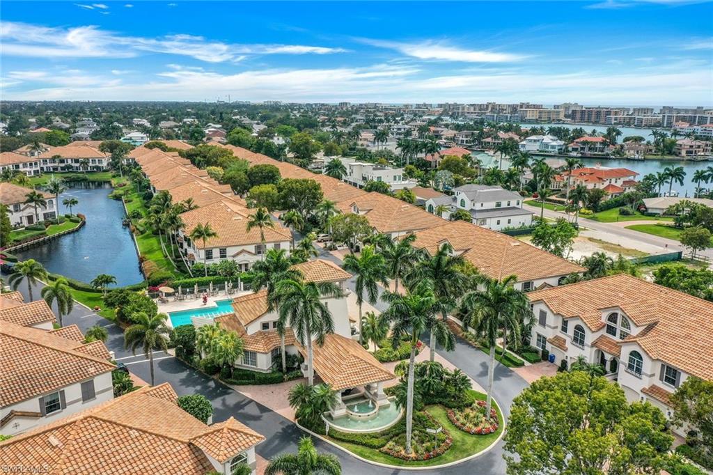 Aerial view of residential area featuring a nearby body of water and a pool area