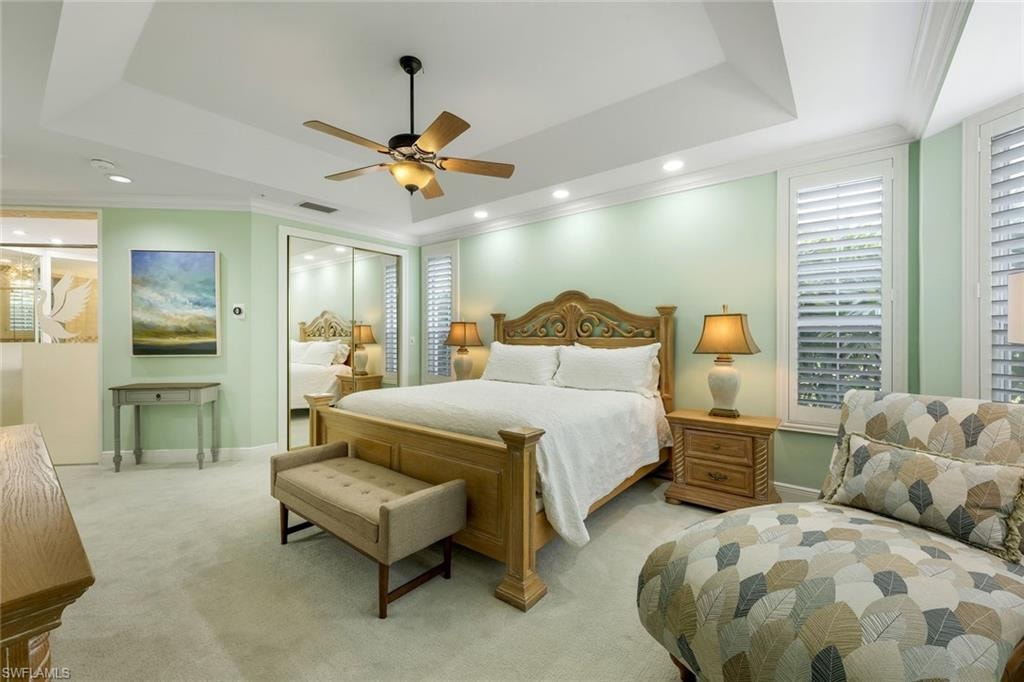 Carpeted bedroom featuring a raised ceiling, crown molding, a ceiling fan, a closet, and recessed lighting
