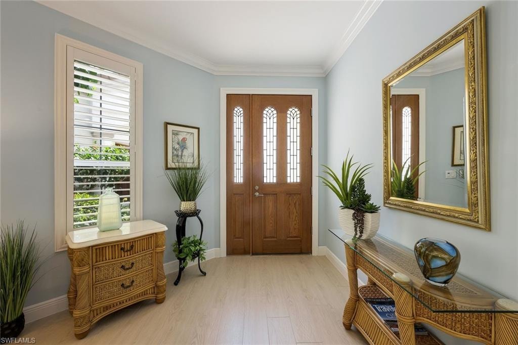 Entryway featuring crown molding and light wood-style floors