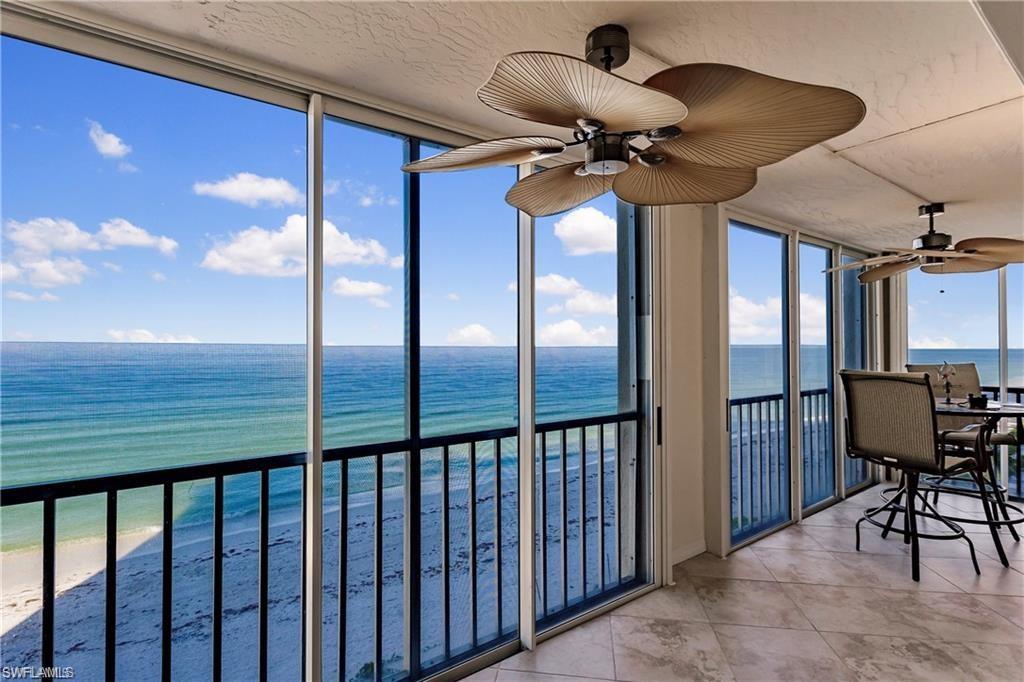 Sunroom with a wall of windows, view of water and beach, and tile patterned floors
