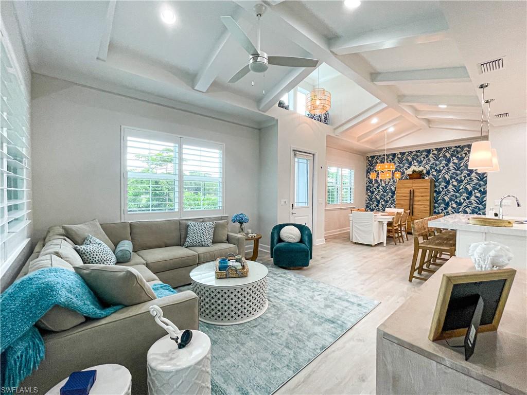 Living room with wood-type flooring, lofted ceiling with beams, and ceiling fan