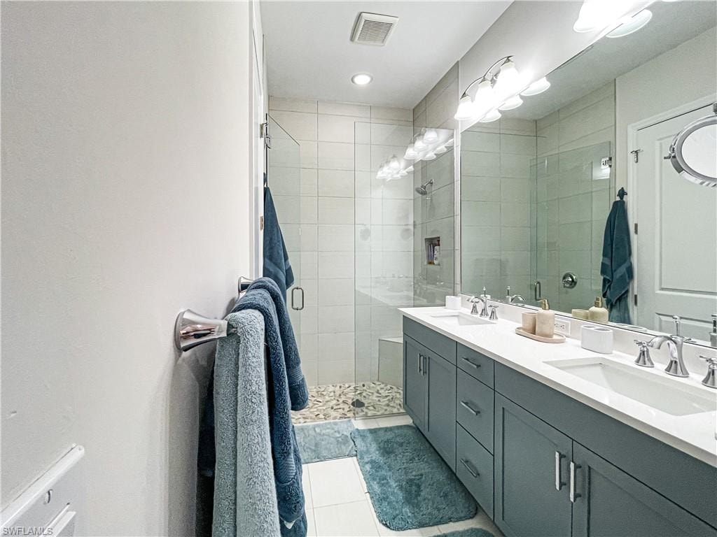Bathroom featuring tile patterned flooring, vanity, and walk in shower