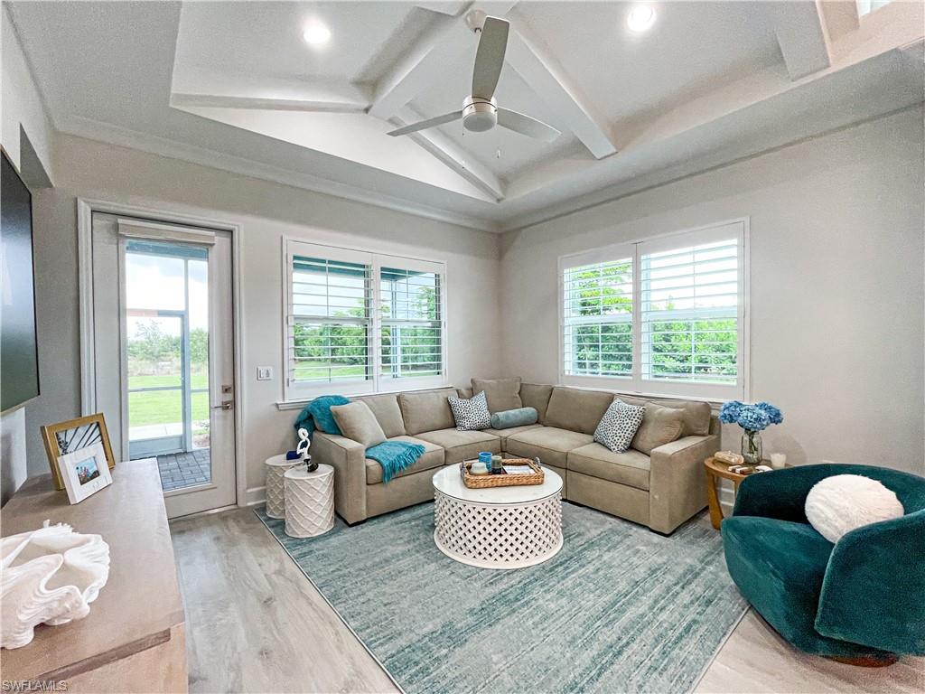 Living room featuring lofted ceiling with beams, hardwood / wood-style flooring, a wealth of natural light, and ceiling fan