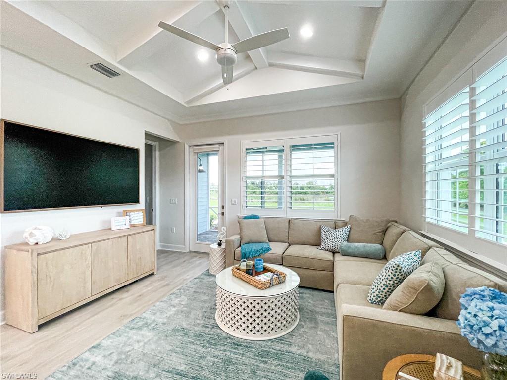 Living room with lofted ceiling with beams, hardwood / wood-style floors, and ceiling fan