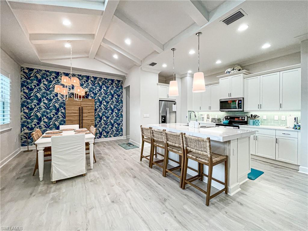 Kitchen featuring appliances with stainless steel finishes, white cabinetry, light hardwood / wood-style flooring, and a large island