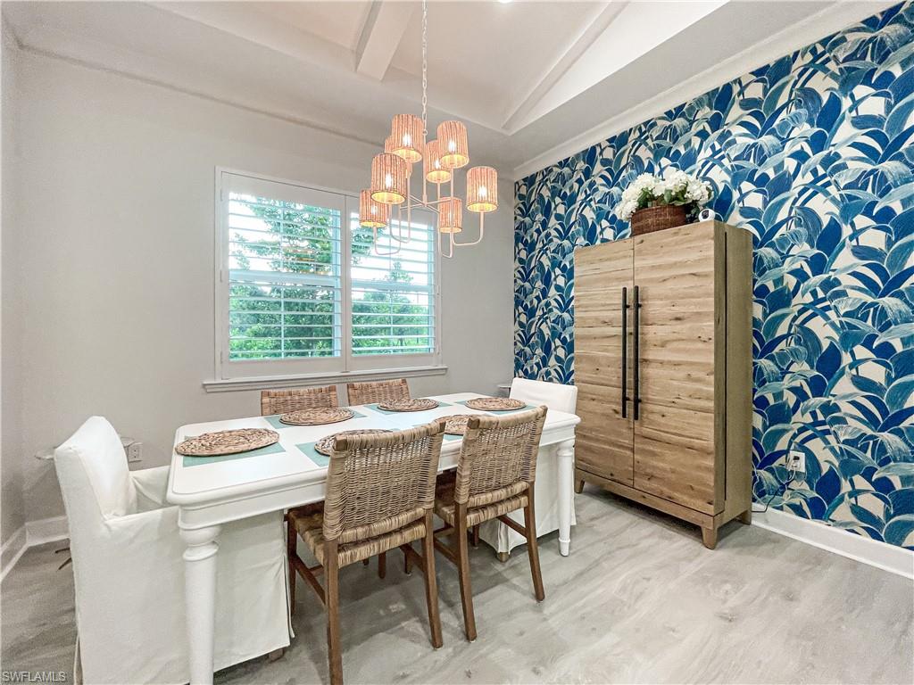 Dining space featuring vaulted ceiling, an inviting chandelier, and hardwood / wood-style flooring
