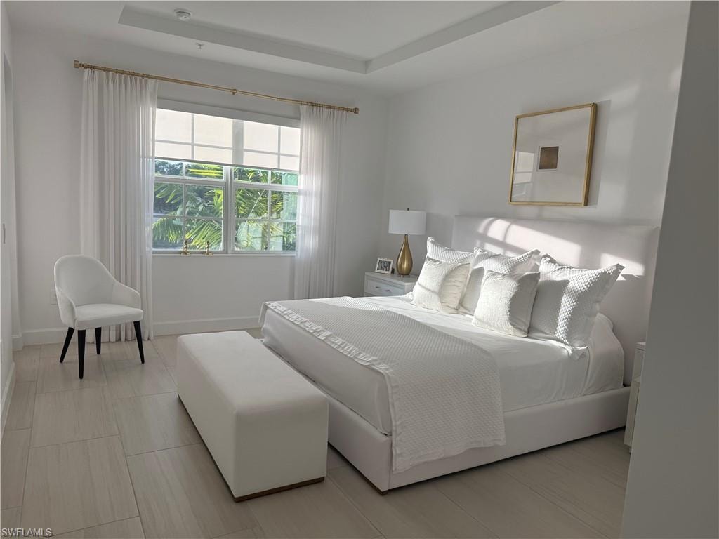 Bedroom with a tray ceiling and baseboards