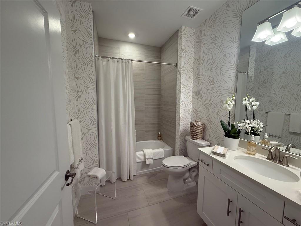 Guest Bathroom with vanity, shower / bath combo with shower curtain, wallpapered walls, light tile patterned flooring, and recessed lighting