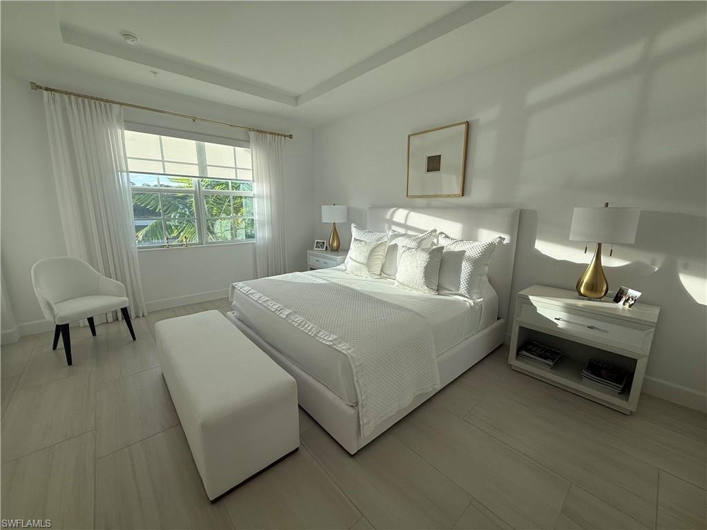 Bedroom featuring a raised ceiling and light wood finished floors
