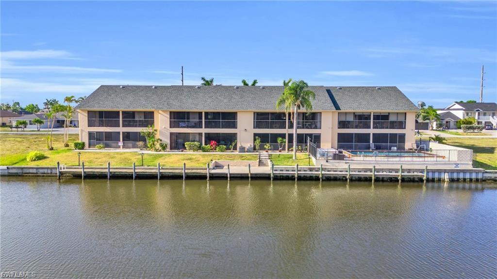 Back of property featuring a water view and a shingled roof