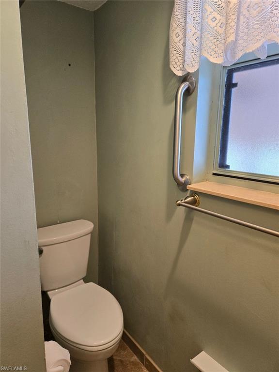 Half bathroom with toilet and baseboards