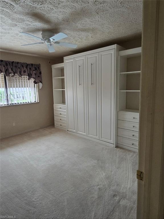 guest bedroom featuring light colored carpet, a textured ceiling, and ceiling fan