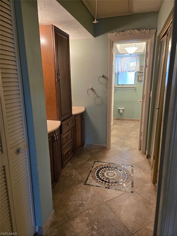 master bath featuring a closet, vanity, dark tile patterned flooring, and a textured ceiling