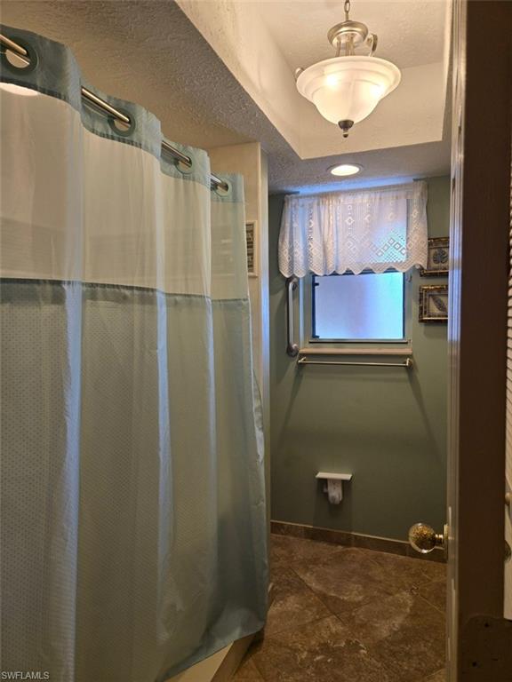 Full bathroom featuring a shower with shower curtain and a textured ceiling