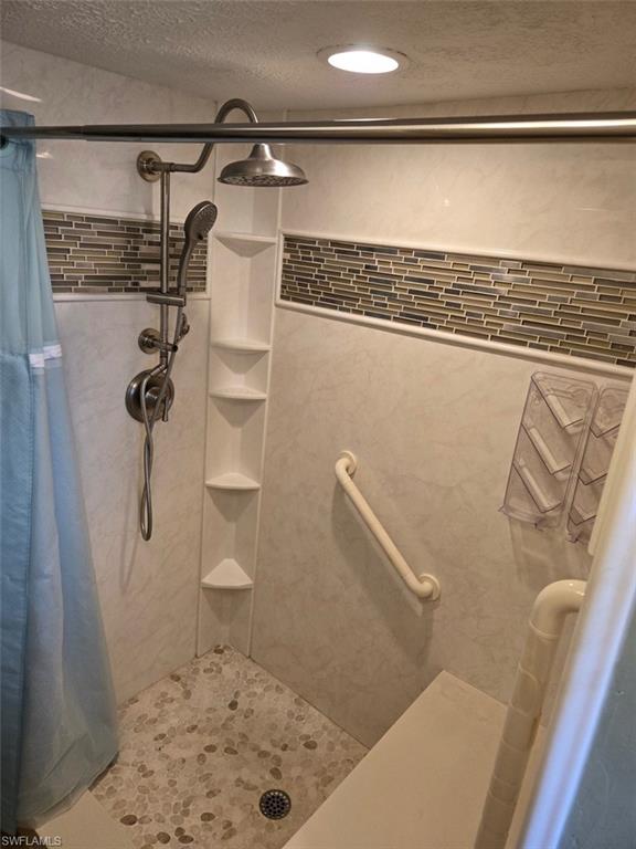 Full bathroom featuring a shower stall and a textured ceiling