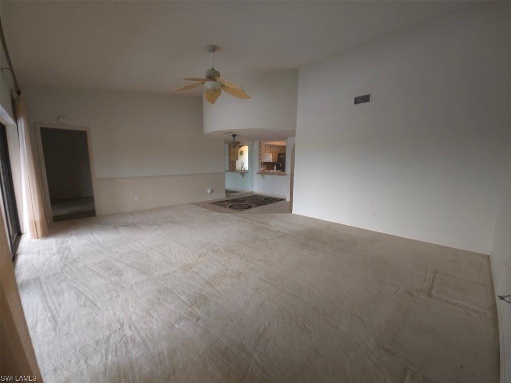 Unfurnished living room featuring carpet flooring and a ceiling fan