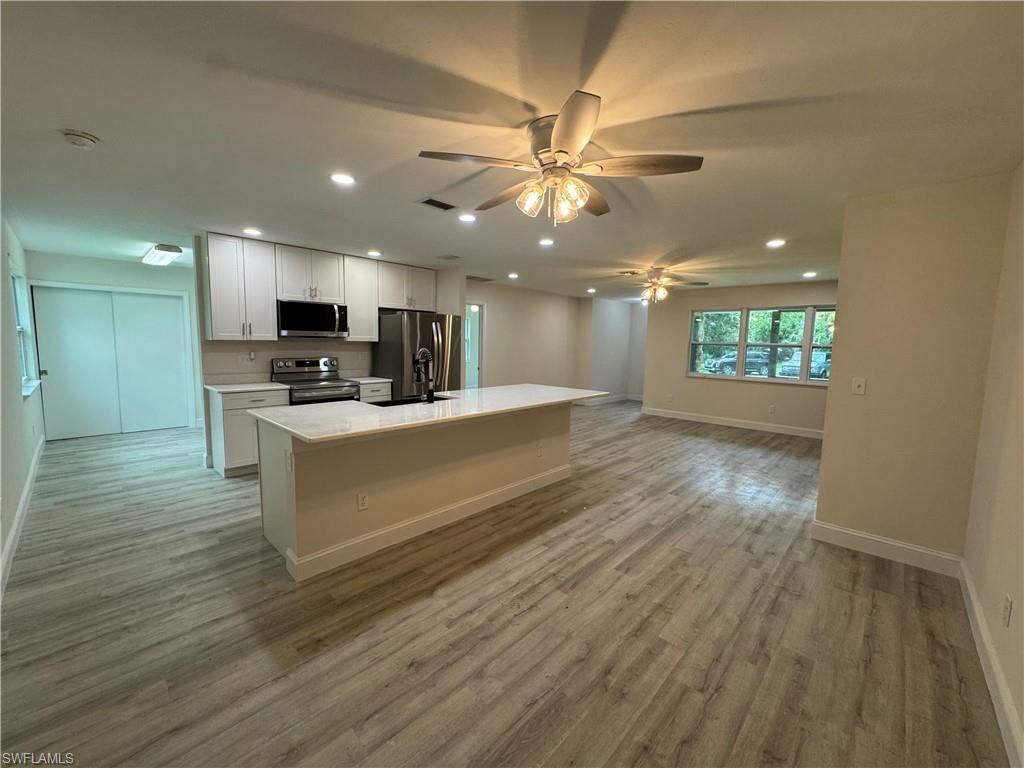Kitchen with open floor plan, an island with sink, recessed lighting, appliances with stainless steel finishes, and white cabinets