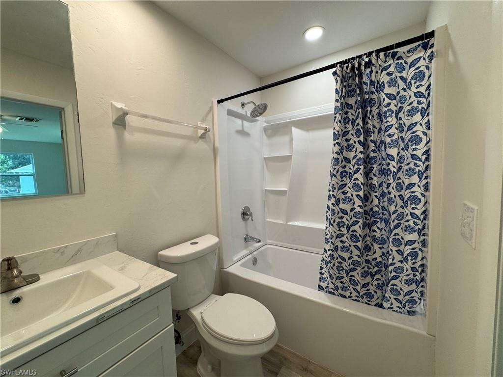 Bathroom with shower / tub combo, vanity, and wood finished floors