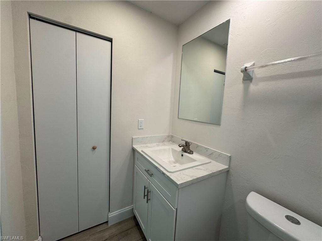 Half bath featuring vanity, dark wood finished floors, and a textured wall