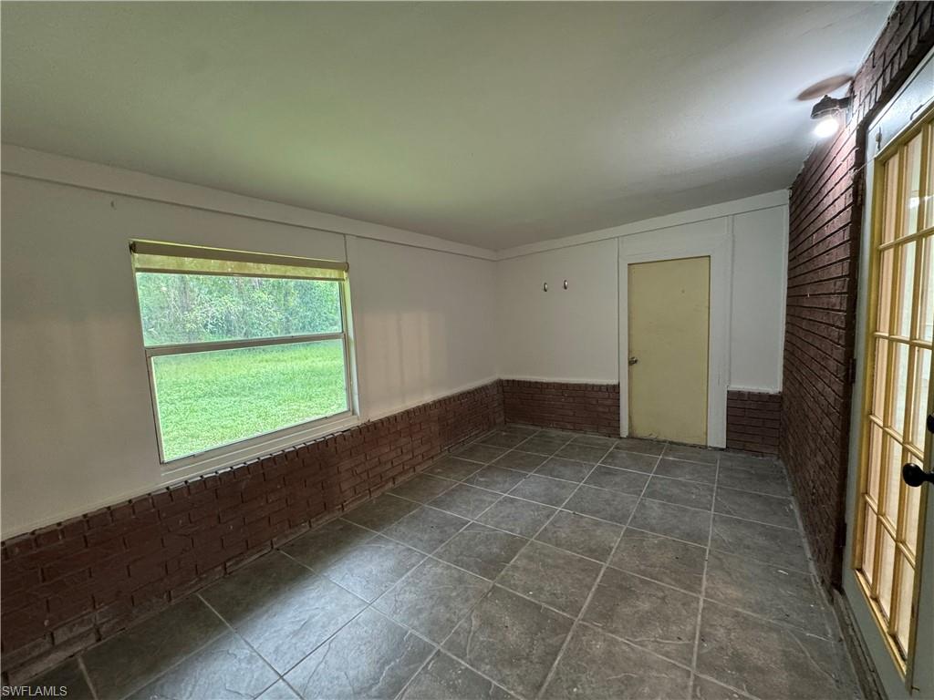 Empty room featuring brick wall and wainscoting
