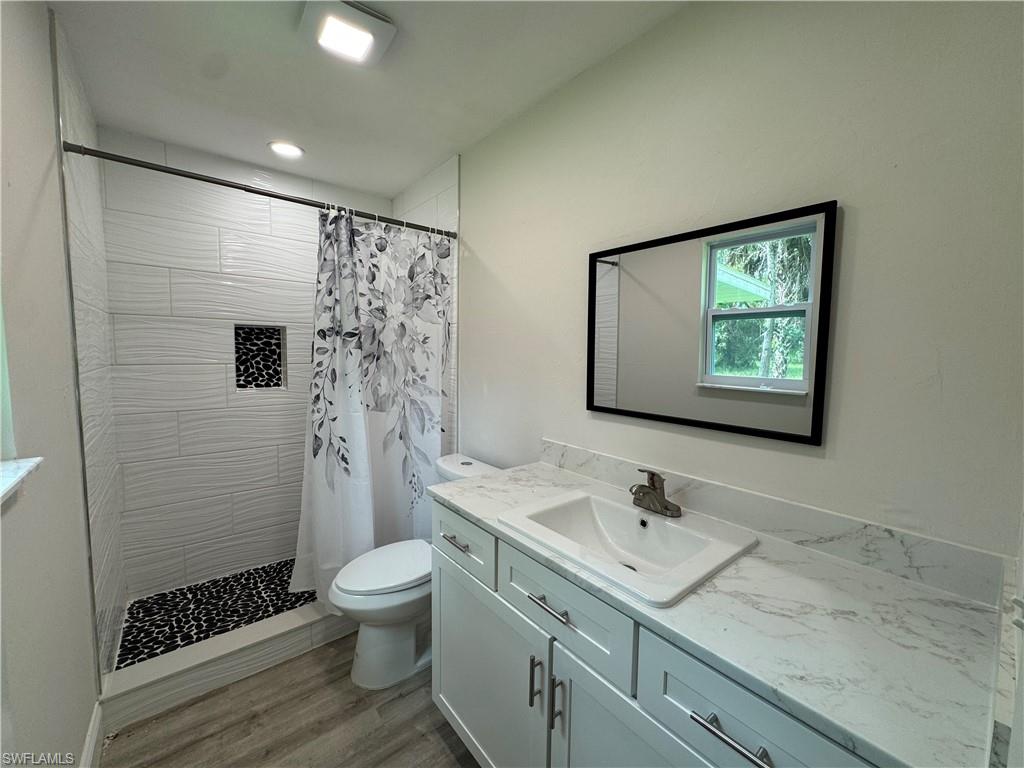 Full bath with vanity, a stall shower, and light wood-type flooring