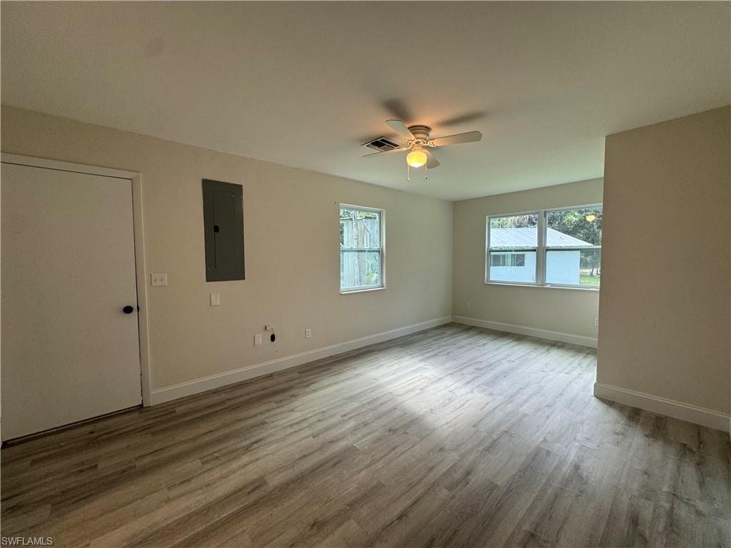Unfurnished room with plenty of natural light, electric panel, light wood-style floors, and a ceiling fan