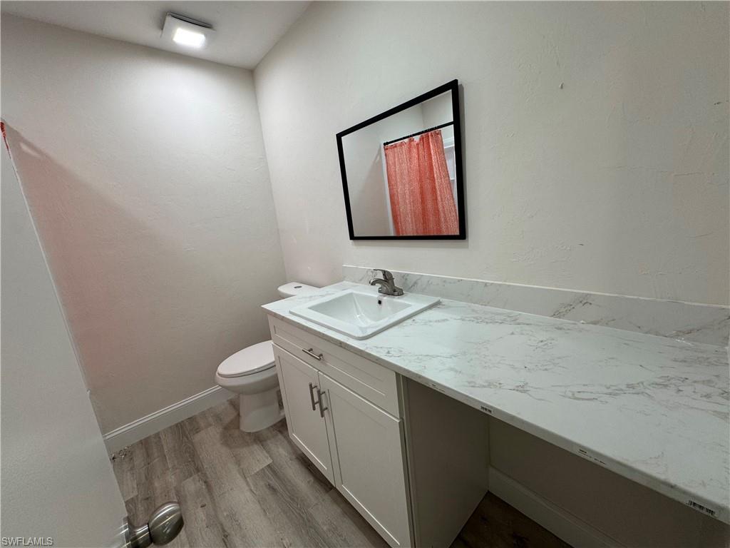Full bath with light wood-style floors, vanity, and a textured wall