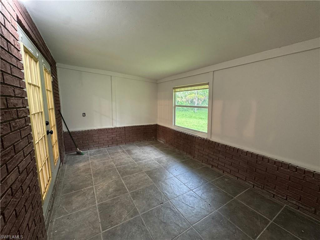 Spare room with wainscoting and brick wall