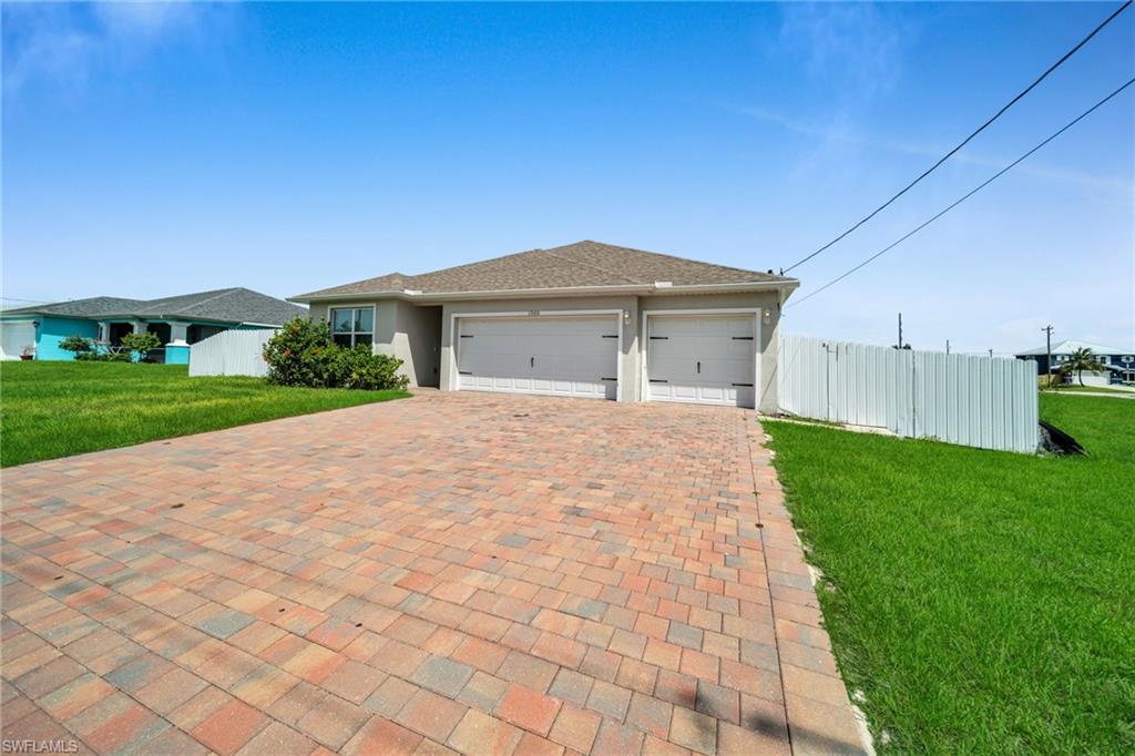 View of front of property featuring a garage, decorative driveway, roof with shingles, and stucco siding