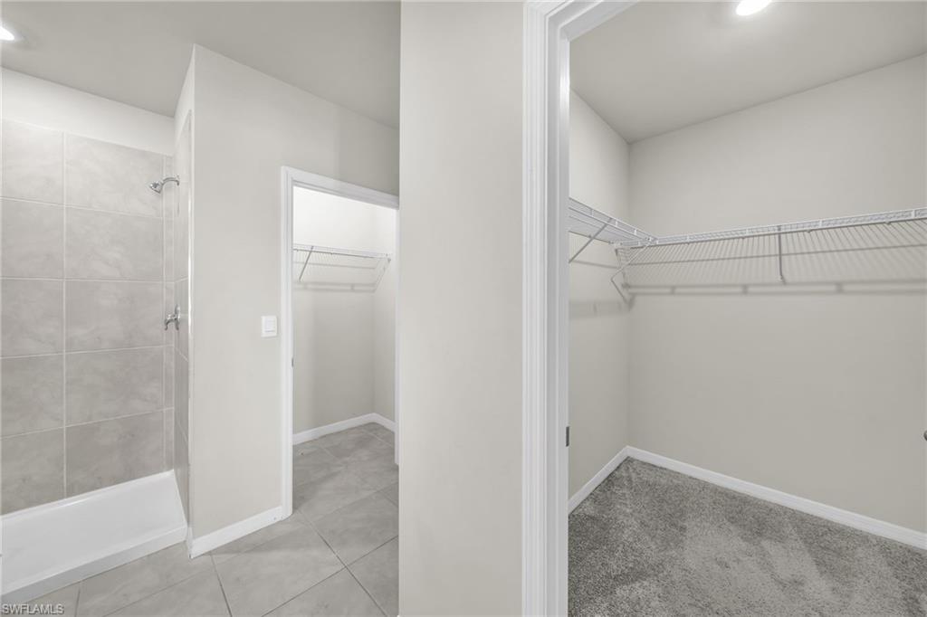 Spacious closet featuring light tile patterned flooring and light colored carpet