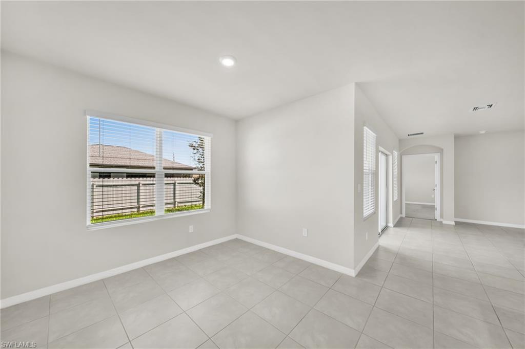 Empty room with arched walkways, light tile patterned floors, and recessed lighting