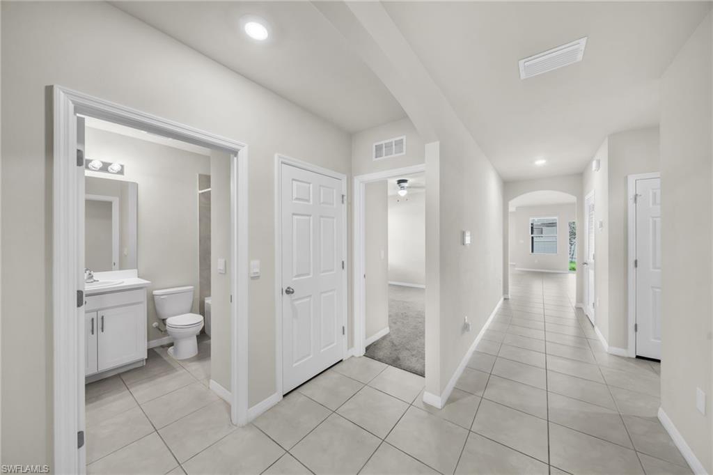 Hall with arched walkways, light tile patterned floors, and recessed lighting