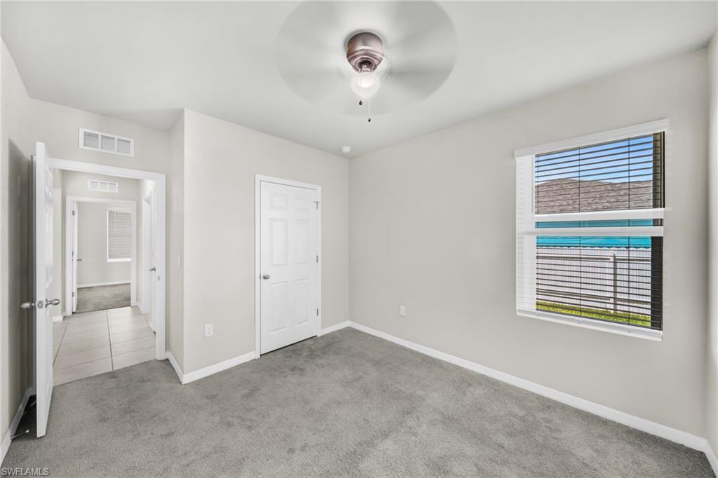 Unfurnished bedroom with light colored carpet and a ceiling fan
