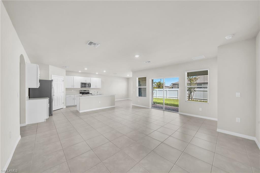 Unfurnished living room with light tile patterned flooring, recessed lighting, and arched walkways