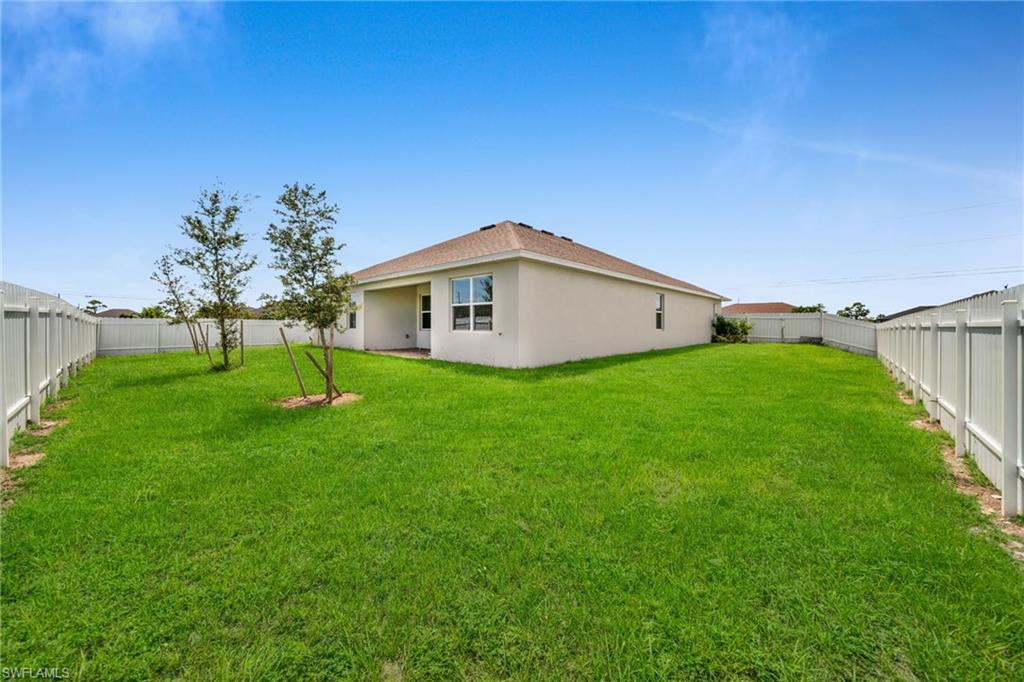 Back of property with a fenced backyard, stucco siding, and a patio area