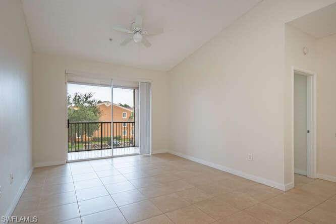 Spare room featuring ceiling fan, vaulted ceiling, and light tile floors