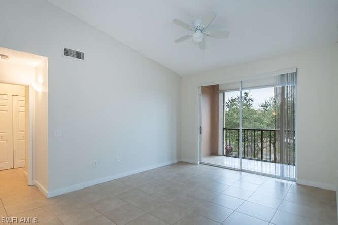 Tiled spare room featuring vaulted ceiling and ceiling fan