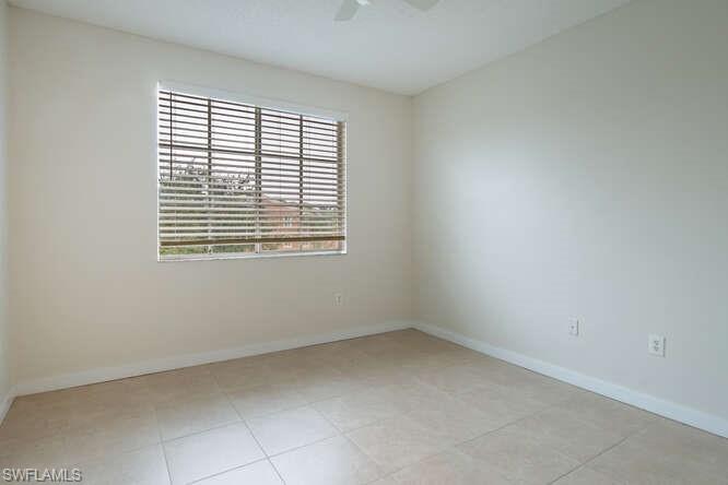 Spare room with ceiling fan, a healthy amount of sunlight, and light tile floors