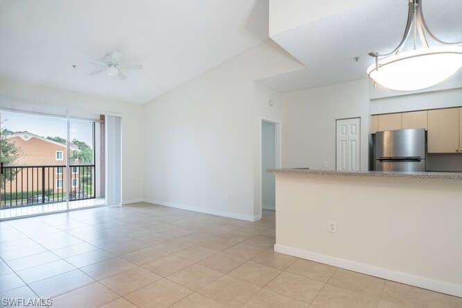 Kitchen with hanging light fixtures, stainless steel fridge, ceiling fan, light tile floors, and light brown cabinets