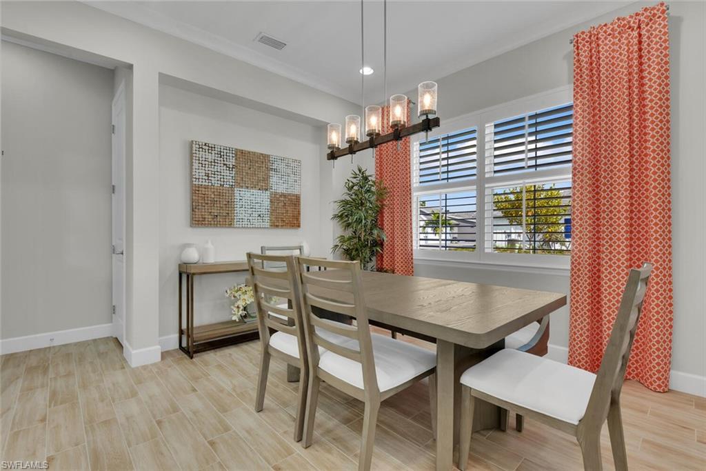 Dining room with an inviting chandelier, crown molding, and light hardwood / wood-style flooring