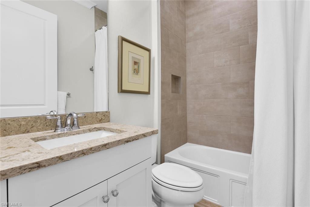 Full bathroom featuring toilet, shower / tub combo with curtain, and vanity