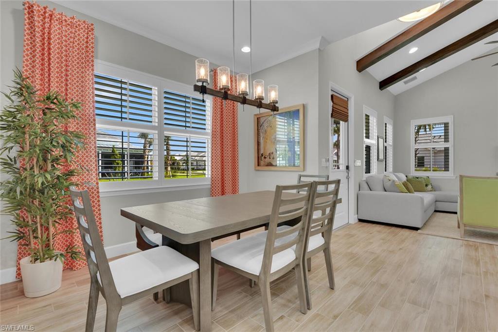 Dining room with lofted ceiling with beams, a chandelier, and light hardwood / wood-style floors