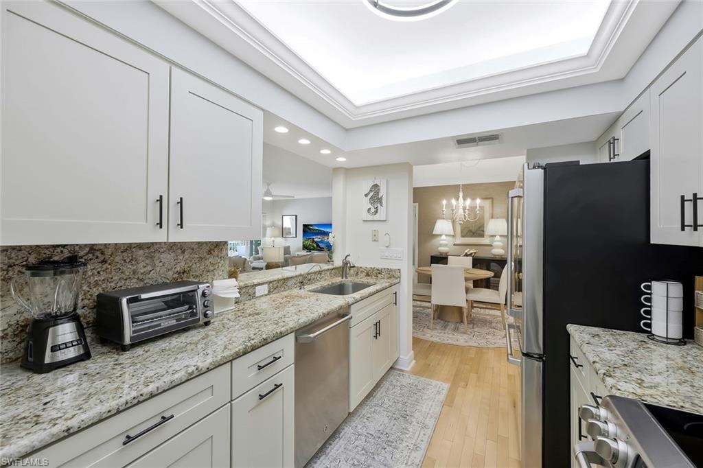 Kitchen with light stone counters, recessed lighting, stainless steel appliances, light wood-style flooring, and a chandelier